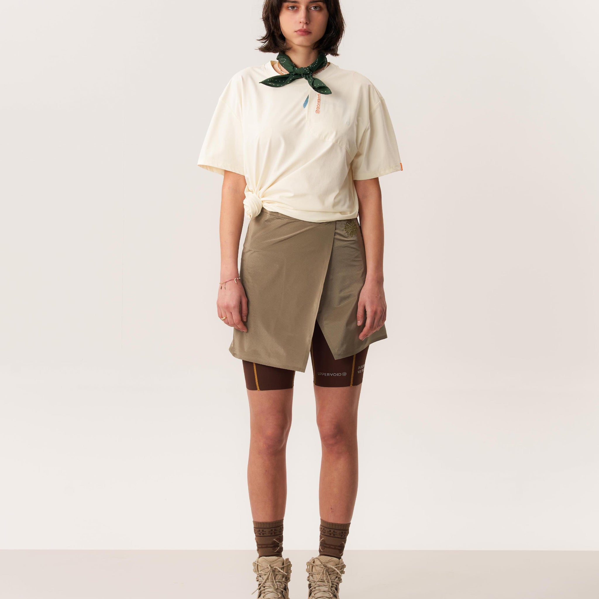 Studio shot of model wearing moisture wicking short-sleeved Ō TEE 2.0 t-shirt and MORO hardshell short skirt in neutral tones