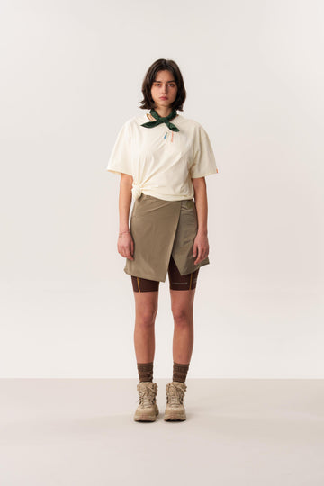 Studio shot of model wearing moisture wicking short-sleeved Ō TEE 2.0 t-shirt and MORO hardshell short skirt in neutral tones