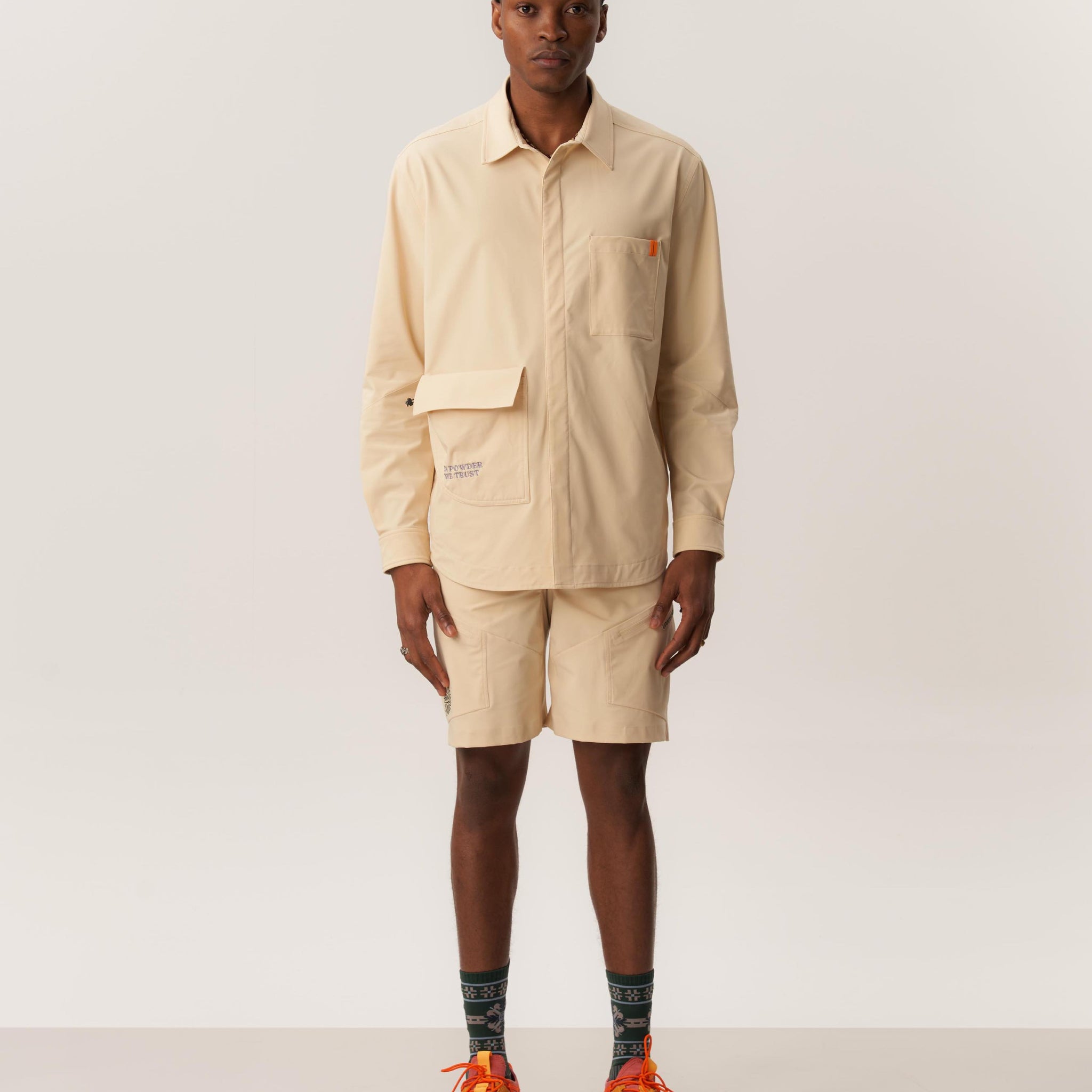 Model wearing khaki overshirt and matching wrinkled shorts in studio setting