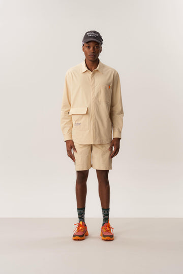 Model wearing khaki overshirt and matching wrinkled shorts in studio setting