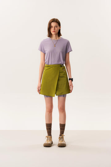 Studio shot of model wearing green short mini skirt and merino wool base layer T-shirt