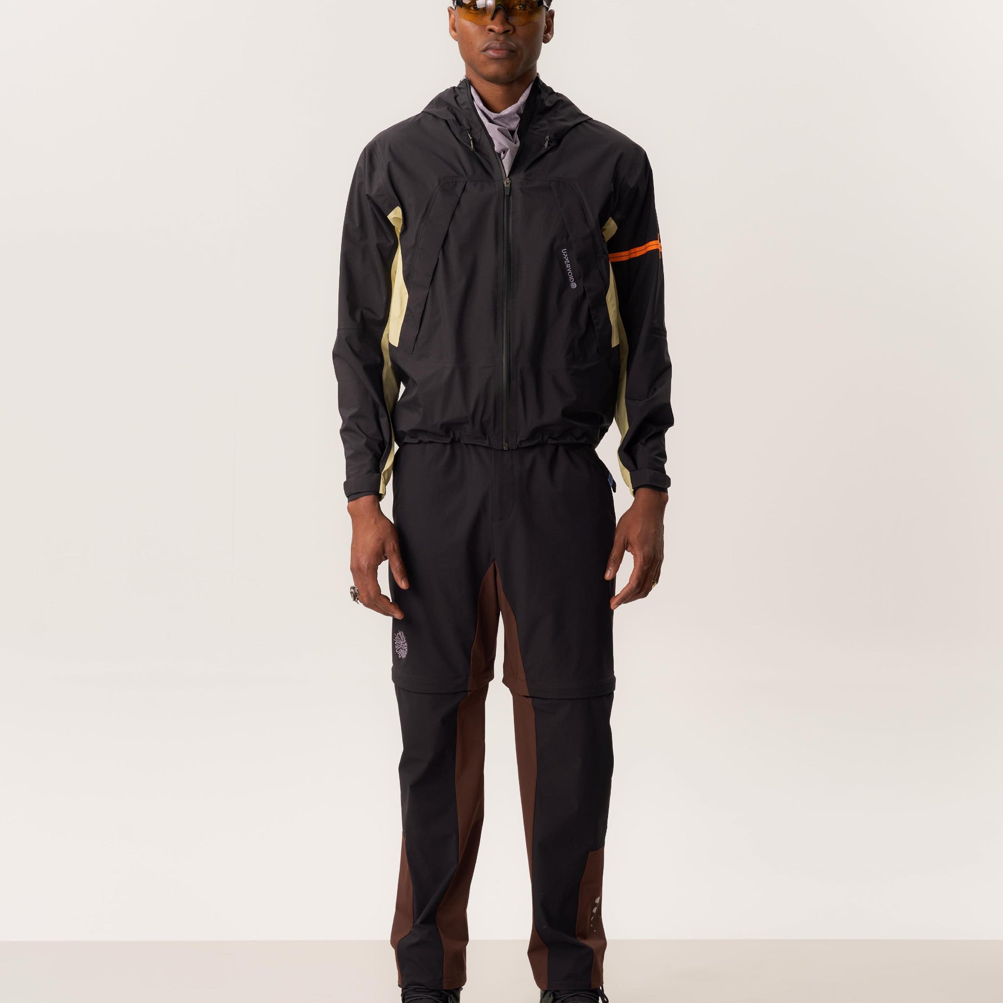 Model wearing  ENIA waterproof hardshell jacket and ATTILA S convertible trekking pants in a controlled indoor studio scene
