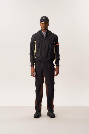 Model wearing  ENIA waterproof hardshell jacket and ATTILA S convertible trekking pants in a controlled indoor studio scene