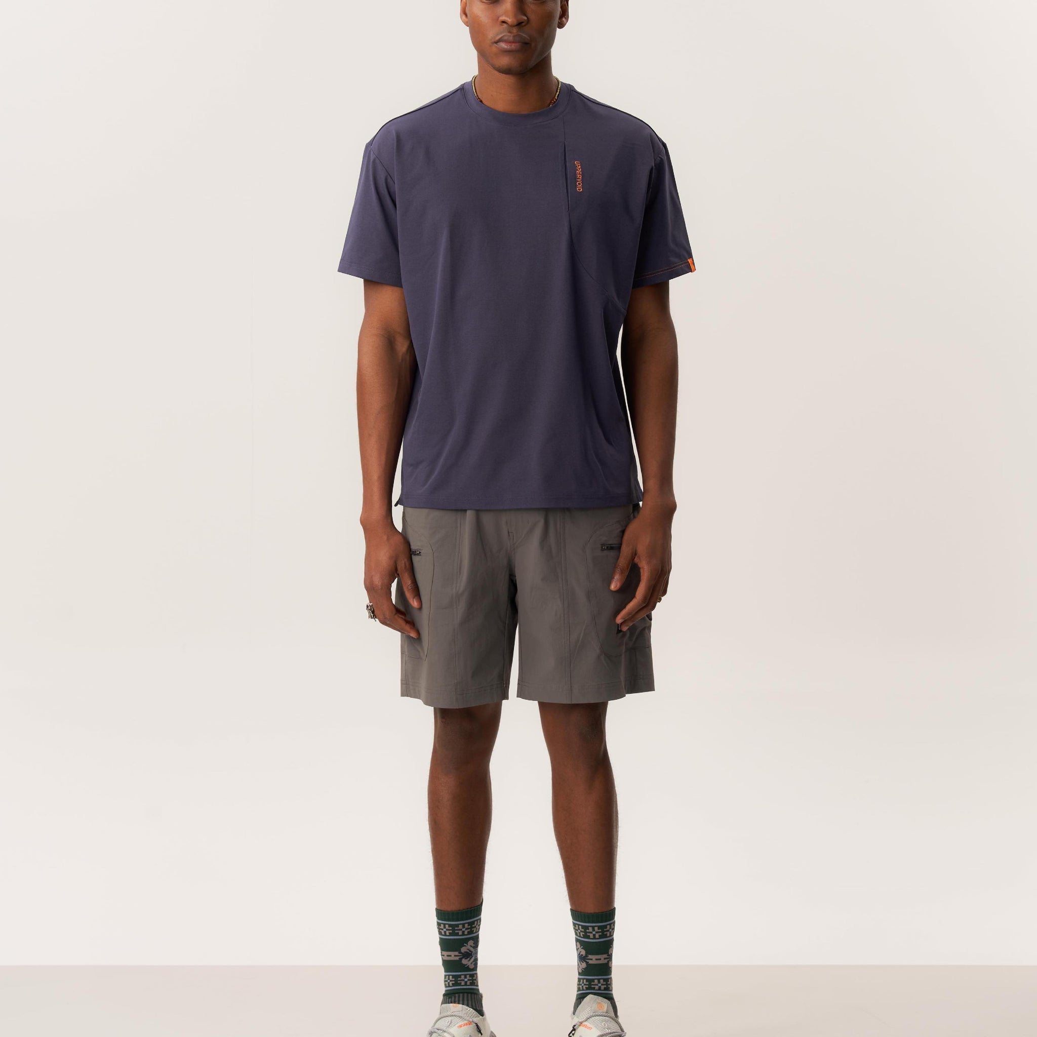 Model wearing a Ō TEE 2.0 moisture-wicking rare bird print t-shirt and WUNAMBAL cordura fabric shorts with multiple pockets in indoor lighting