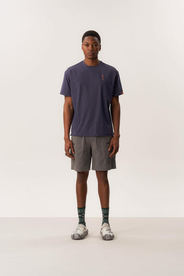 Model wearing a Ō TEE 2.0 moisture-wicking rare bird print t-shirt and WUNAMBAL cordura fabric shorts with multiple pockets in indoor lighting