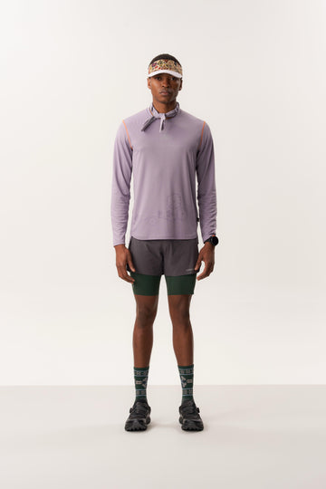 Model wearing a UPF Polartec Power Dry long sleeve shirt with quick-drying best trail running shorts in a studio setting