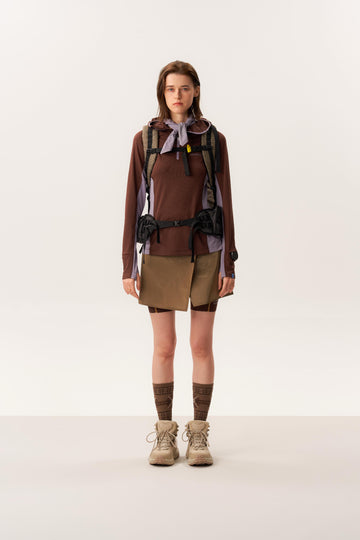 Model wearing moisture-wicking quarter zip pullover and waterproof hiking skirt with short silhouette in studio lighting