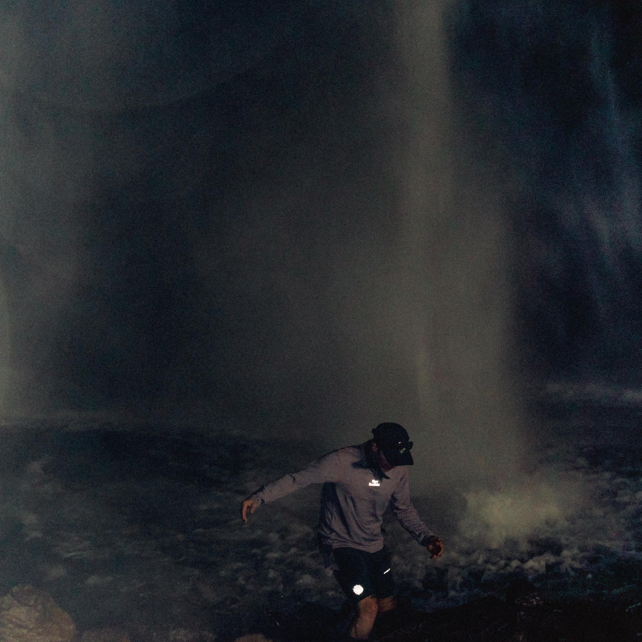 Model running into mist-filled cave environment in dark activewear, highlighting movement and exploration